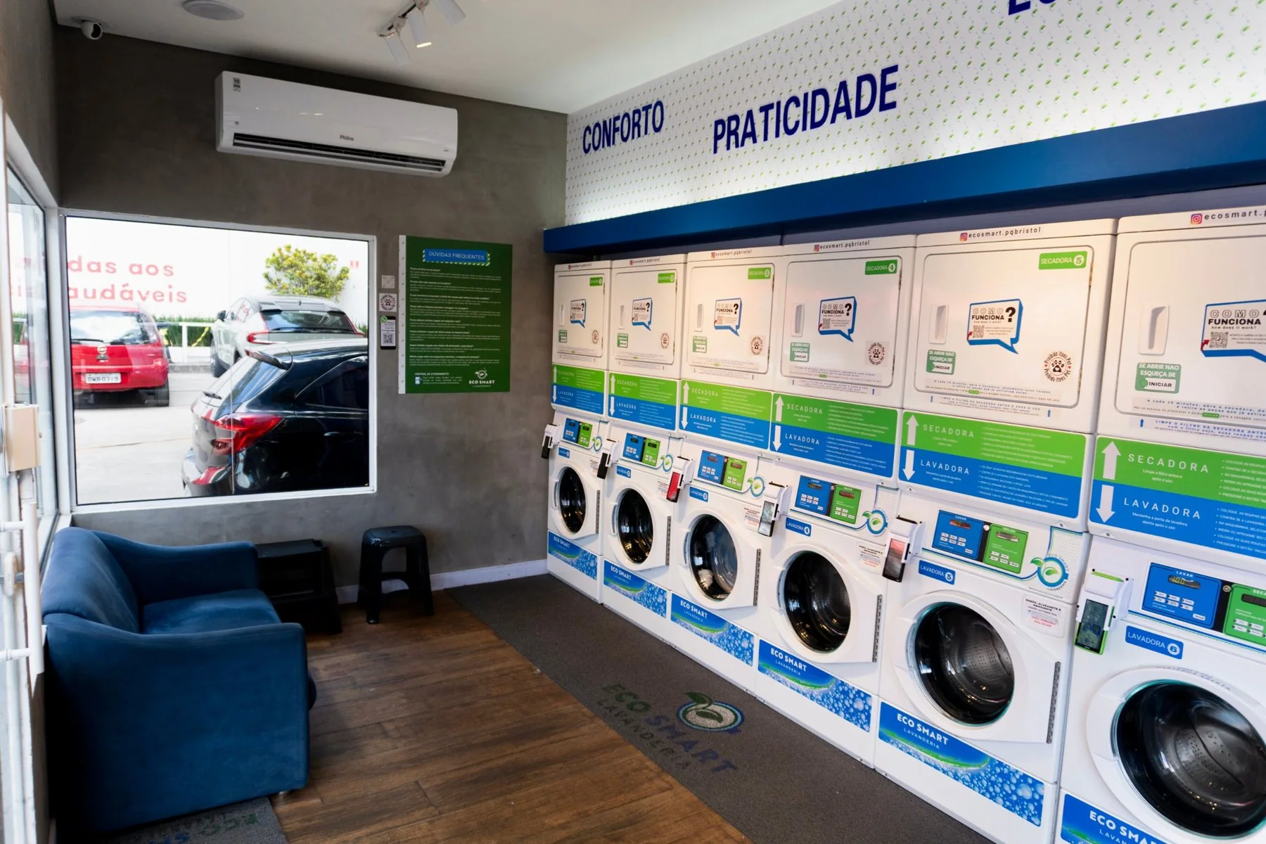 Interior de uma lavanderia Eco Smart com lavadoras, secadoras e sofá para espera